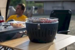 LotusGrill XL Hybrid Houtskoolbarbecue - Rood -Kampeeruitrusting lotusgrill in gebruik met toppy shirtje 2